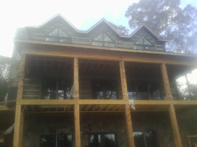 Dormers and porch framing on a large log home under construction — Roof Coating work by our crew in Charlestown