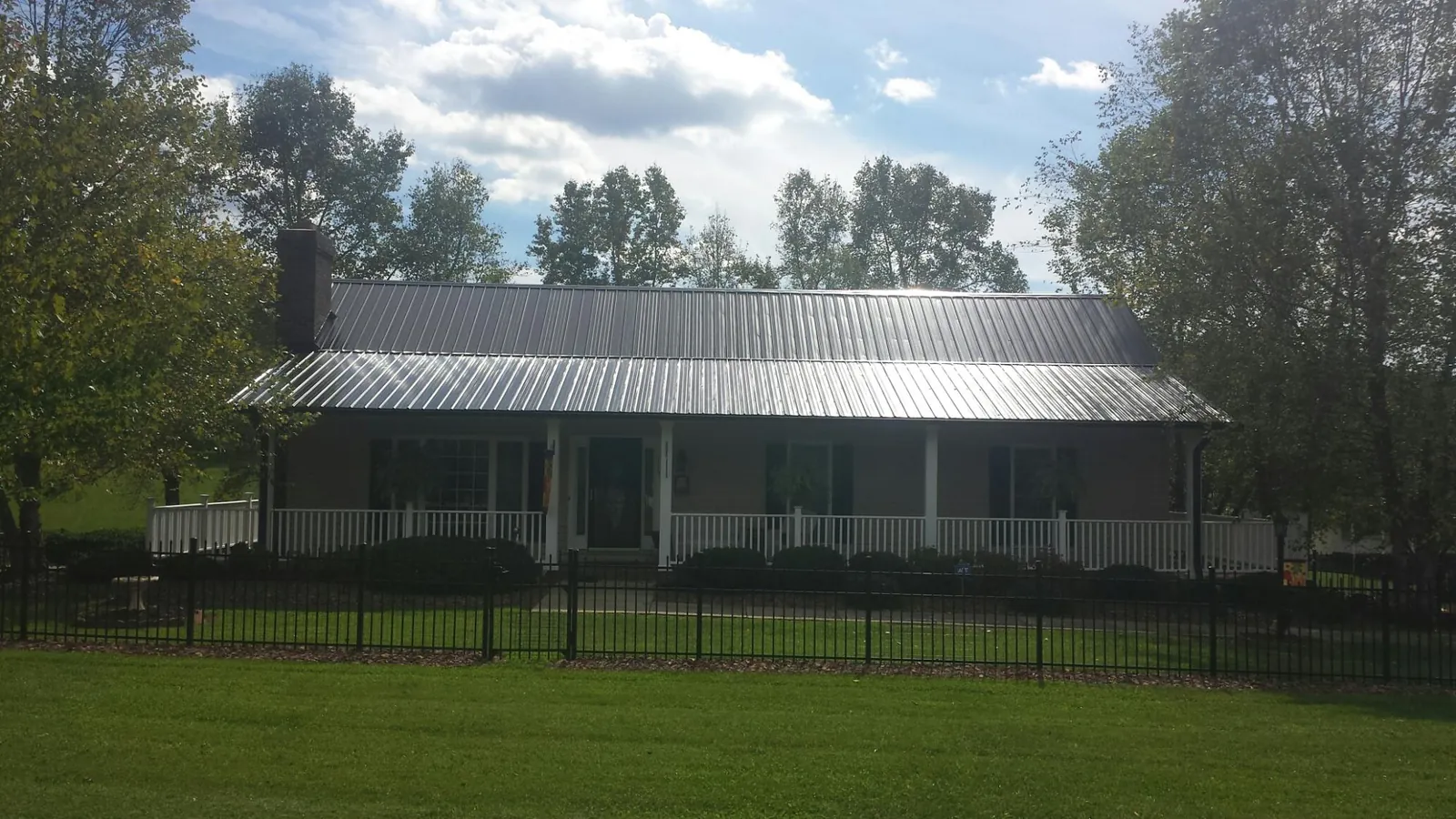 Gray metal roof on a brick ranch with a full width front porch — Gutter Guard Installation work by our crew in Charlestown